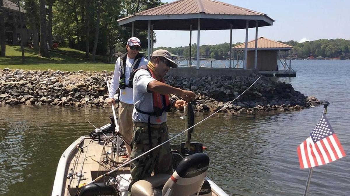 James McDougal removes the hook from a spotted bass he battled to catch for 1 1/2 hours on Lake Norman Thursday.