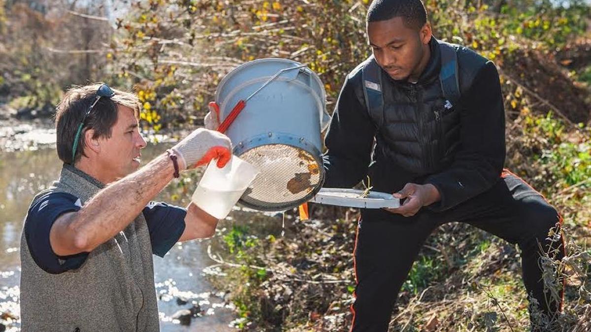 Environmental scientist Reed Perkins works in a stream with Queens student Darryl White in this 2014 photo.