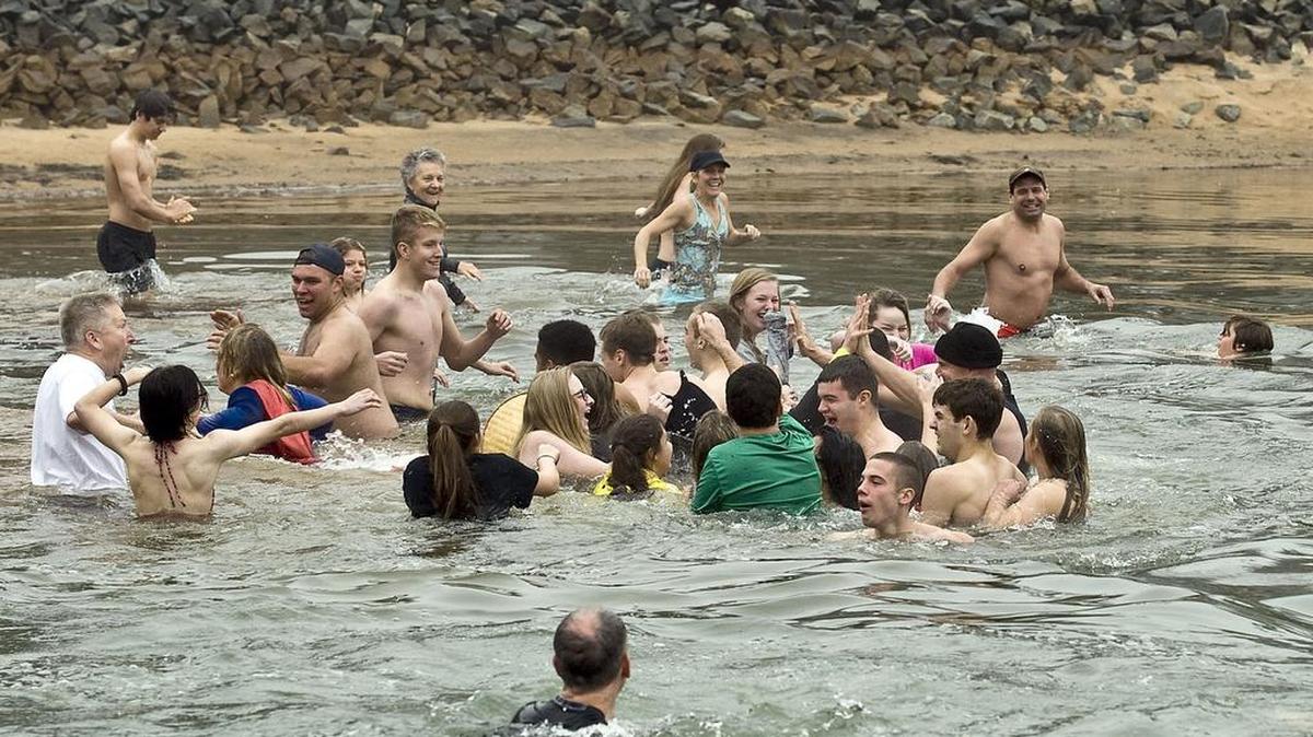 Swimmers give a high five to Mooresville High School JROTC Chief Stephen Tate, right, in knit cap, before heading back to shore during the Polar Plunge on Jan. 21.