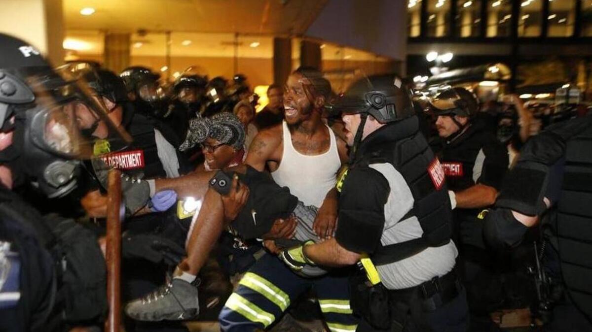 Police and protesters carry Justin Carr into the parking area of the Omni Hotel during a march to protest the death of Keith Scott.