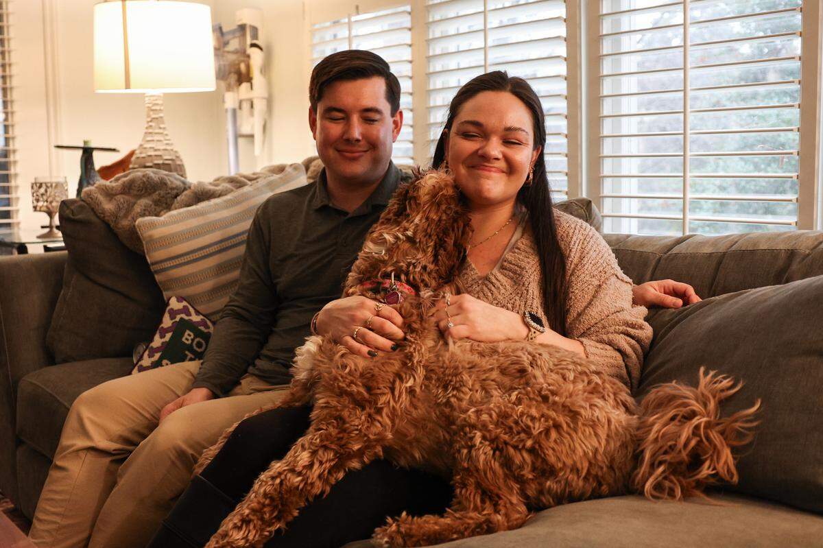 Will Adams, left, his fiancee, Clara Vengoechea, and their dog, Mila, at their Charlotte home on March 10. The couple were supposed to be married at Champagne Manor on May 17 before the venue went into foreclosure.