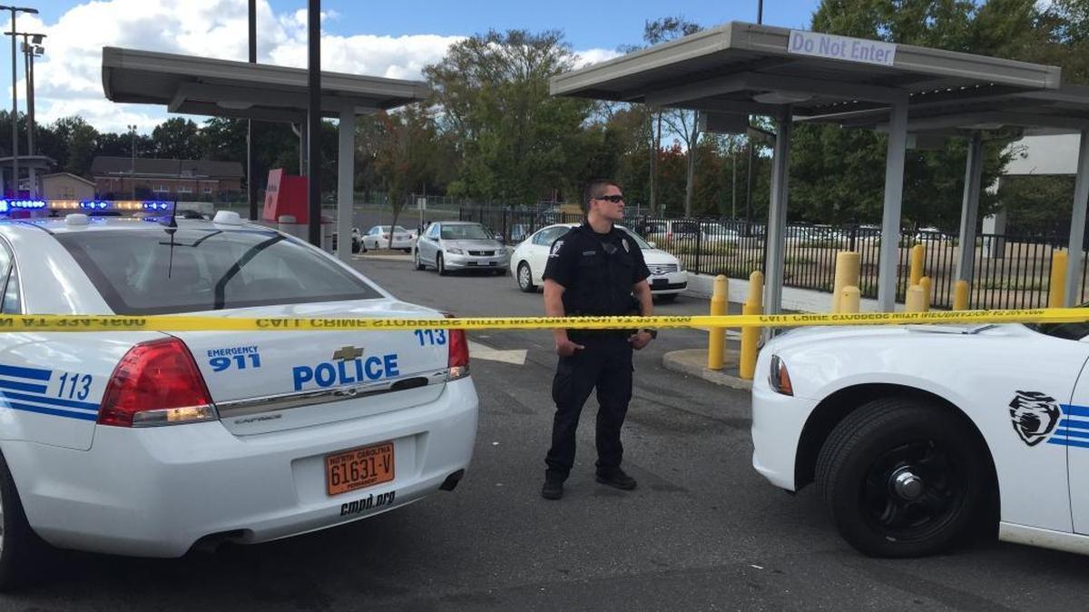 
A Charlotte-Mecklenburg police officer stands guard behind police tape as detectives investigate a shooting at a Bank of America branch on Beatties Ford Road. 
