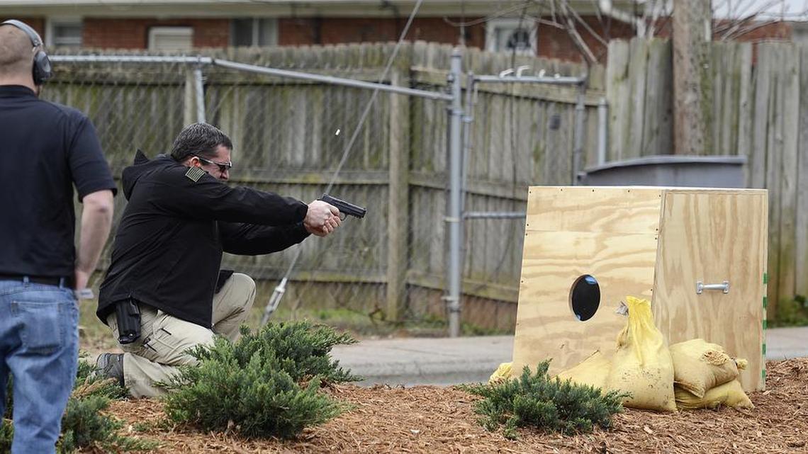 A shell casing flies as CMPD training officer Kip White shoots into an enclosure meant to contain a bullet after firing during a 2013 test of the ShotSpotter detection system.