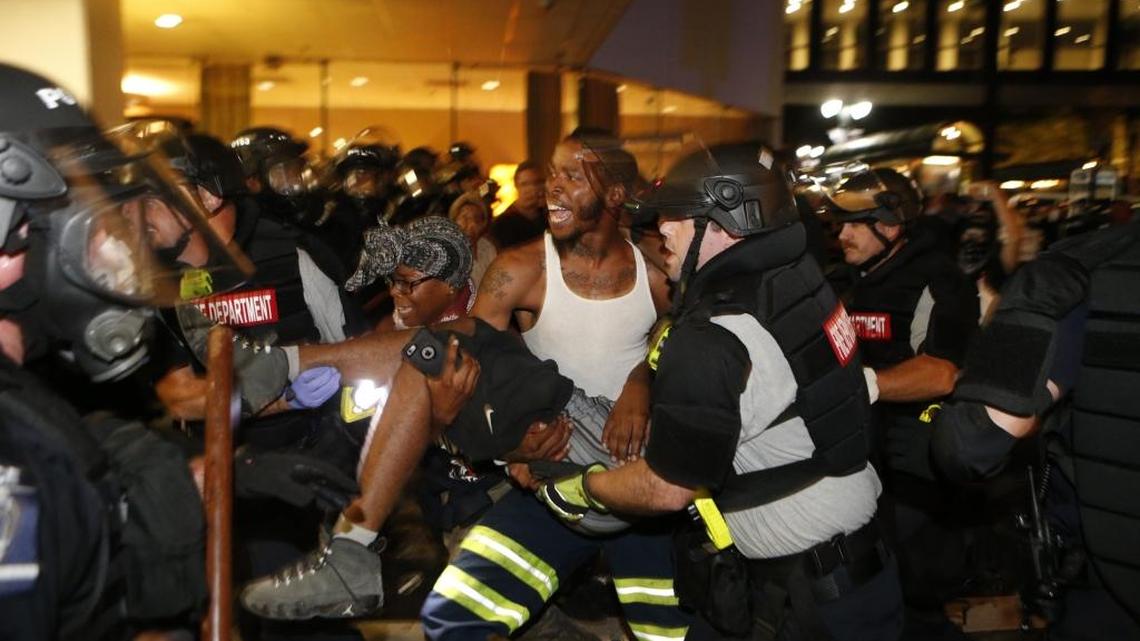 Police and protesters carry a seriously wounded protester into the parking area of the the Omni Hotel during a march to protest the death of Keith Scott September 21, 2016 in Carolina.The man has since died.