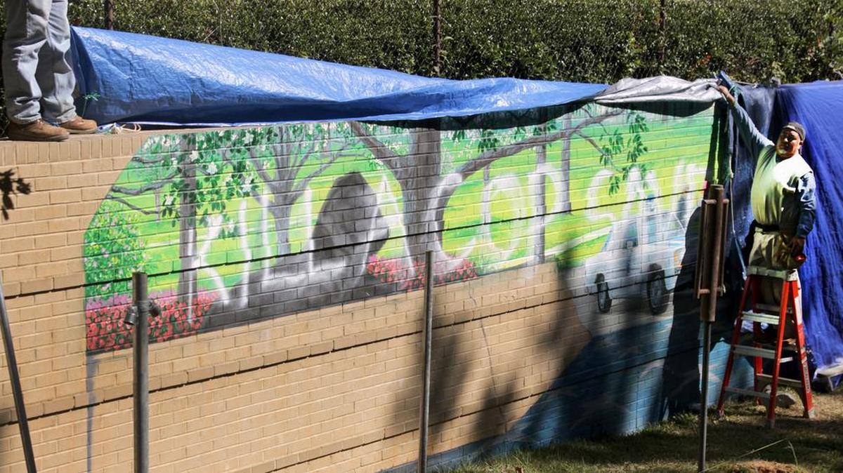 Construction workers pull up the tarp covering the mural, which was spray-painted Thursday night or Friday morning.