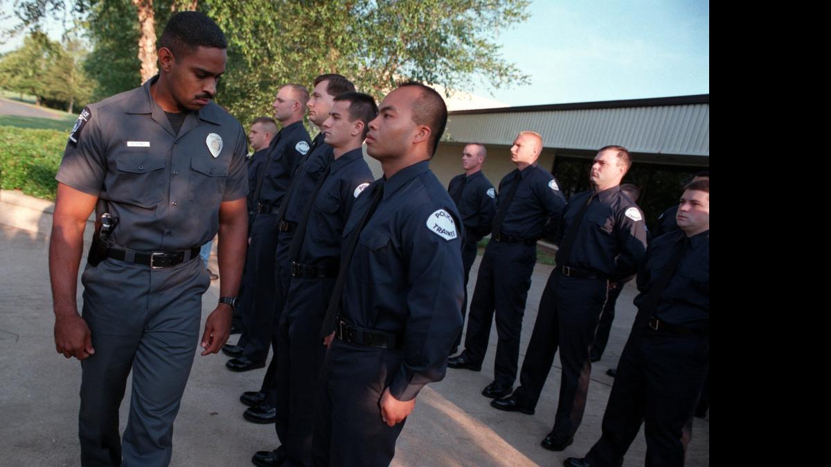 
1997 FILE PHOTO: Officer Kerr Putney inspects new recruits at the Charlotte-Mecklenburg Police Academy, checking their uniforms and grooming to make sure they meet standards.
