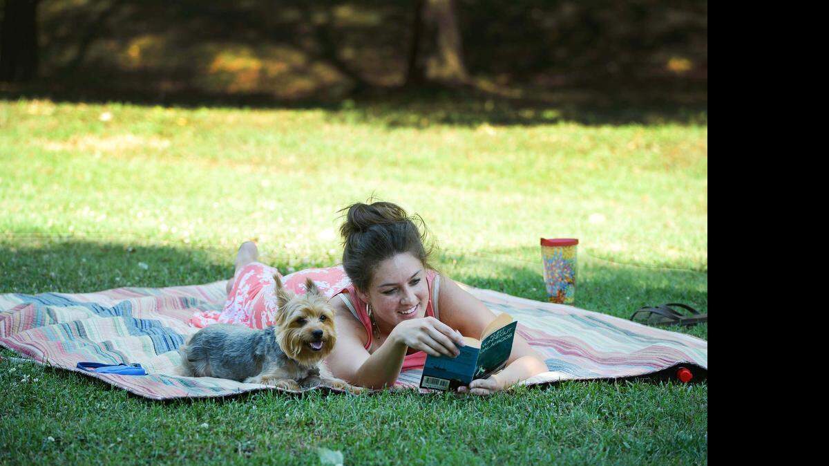 
 Laramie Taylor of Charlotte enjoys the cooler weather while reading a novel at Freedom Park with her Yorkshire Terrier Kai on Sunday “It’s cooled off and it’s wonderful,” Taylor said.
