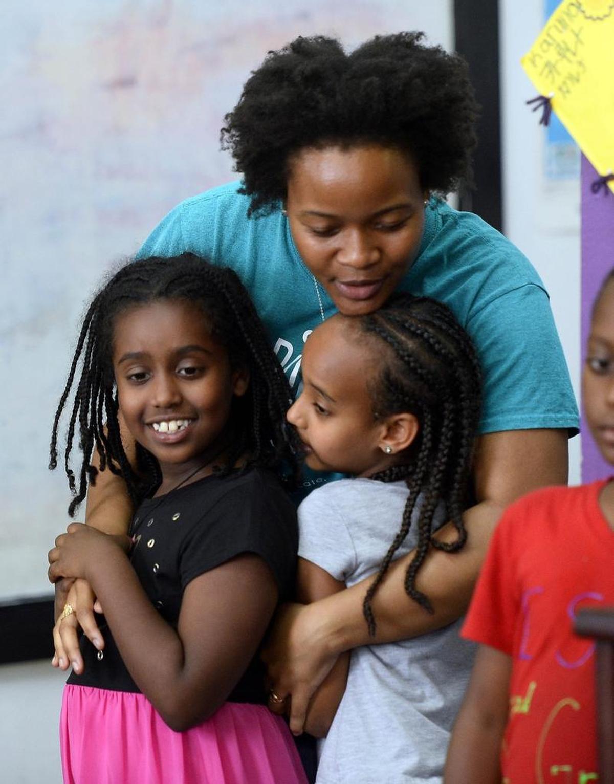 Andriika Clark, a K-2 tutor at OurBRIDGE, gives a hug to students Elsa Asres, left, and Ocean Welbegeire, during a farewell party for the organization’s Plaza Midwood location on Friday, June 9, 2017. The group, an after-school program that helps refugee and immigrant children learn English and adjust to American life, is moving to a new location to accommodate its growing size on the Aldersgate campus alongside other nonprofit organizations