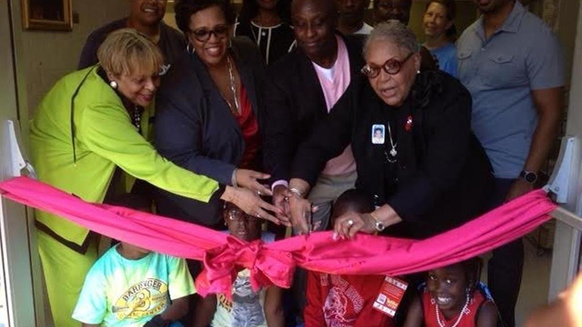Mecklenburg Commissioner Vilma Leake (with scissors), C.W. Williams CEO Debra Weeks (front row standing, second to left) and others cut ribbon during a Sept. 19 health fair to symbolize the rebirth of C.W. Williams Community Health Center.