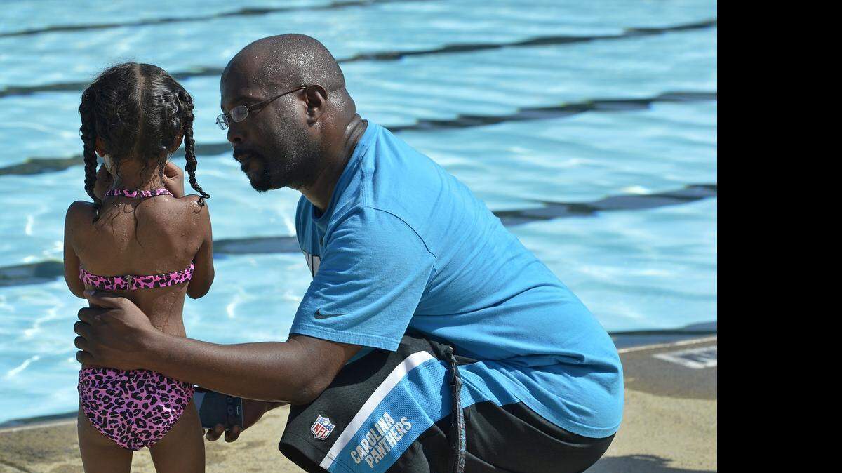 
Jerry Holloway tries to convince his daughter Kaitlyn, 3, to re-enter the pool after a short break during her first swimming lesson hosted by Mecklenburg County Parks & Recreation at Double Oaks Pool on Thursday morning.
