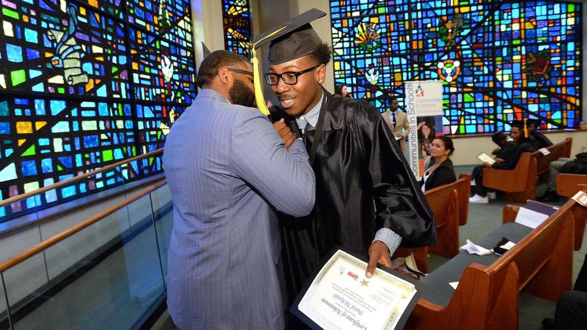 The Rev. Don Thomas Jr. congratulates a student during a June graduation celebration at First Baptist Church West. Mecklenburg County commissioners on Wednesday agreed to give the church’s nonprofit $75,000 to cover its summer program expenses.
