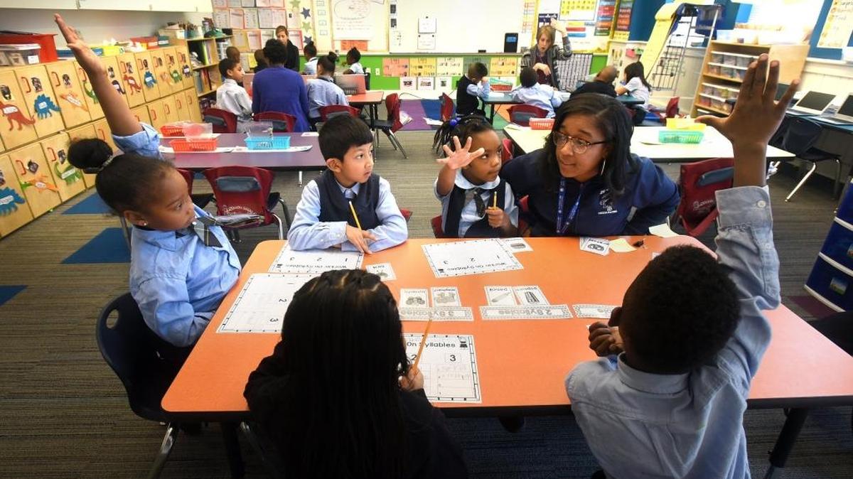 Teacher's aide Elizabeth Young (left) asks a question of her students during an English lesson at the Maureen Joy Charter School in Durham. A new study says that charter schools are costing the Durham Public Schools between $500 and $700 per student.