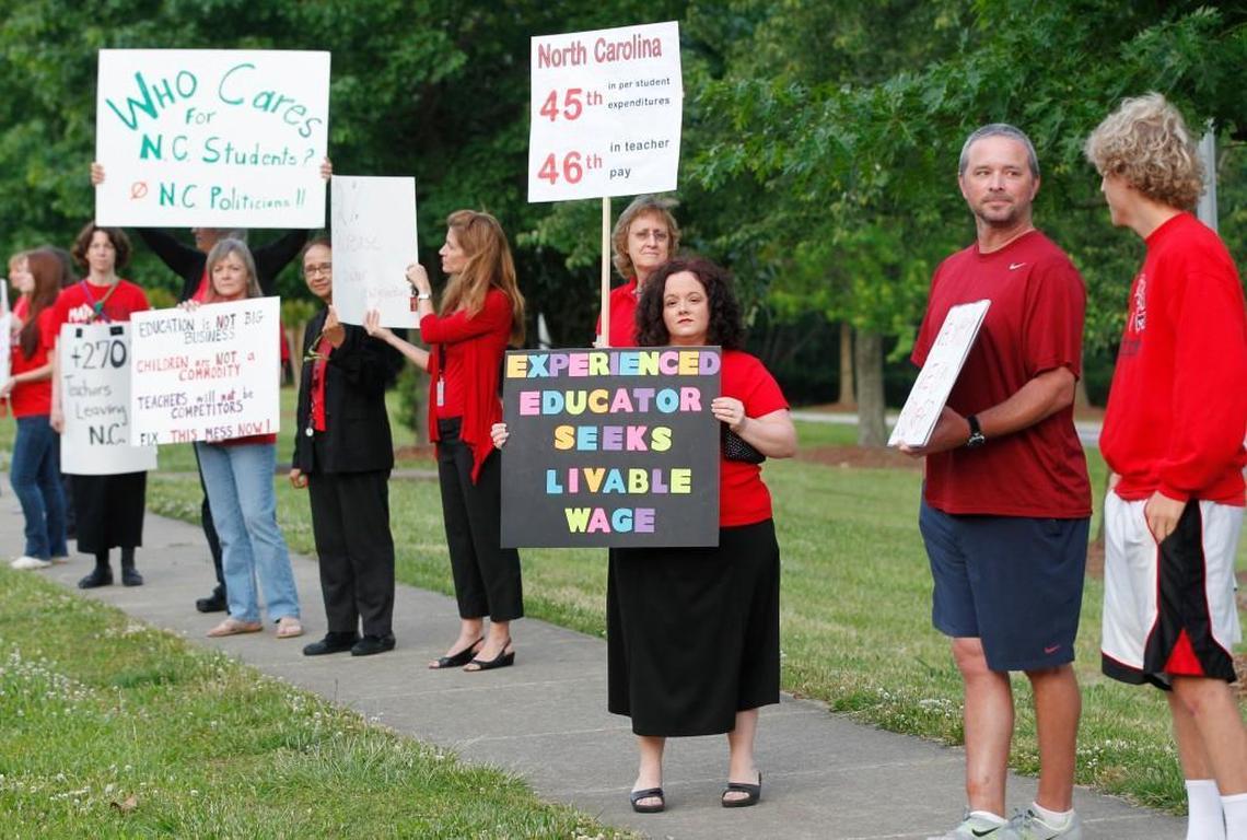 Teachers, including Kristin VanBuskirk, center, a math teacher at Apex High School, rally against high turnover and low pay on the sidewalk in front of Apex High School on May 21, 2014.