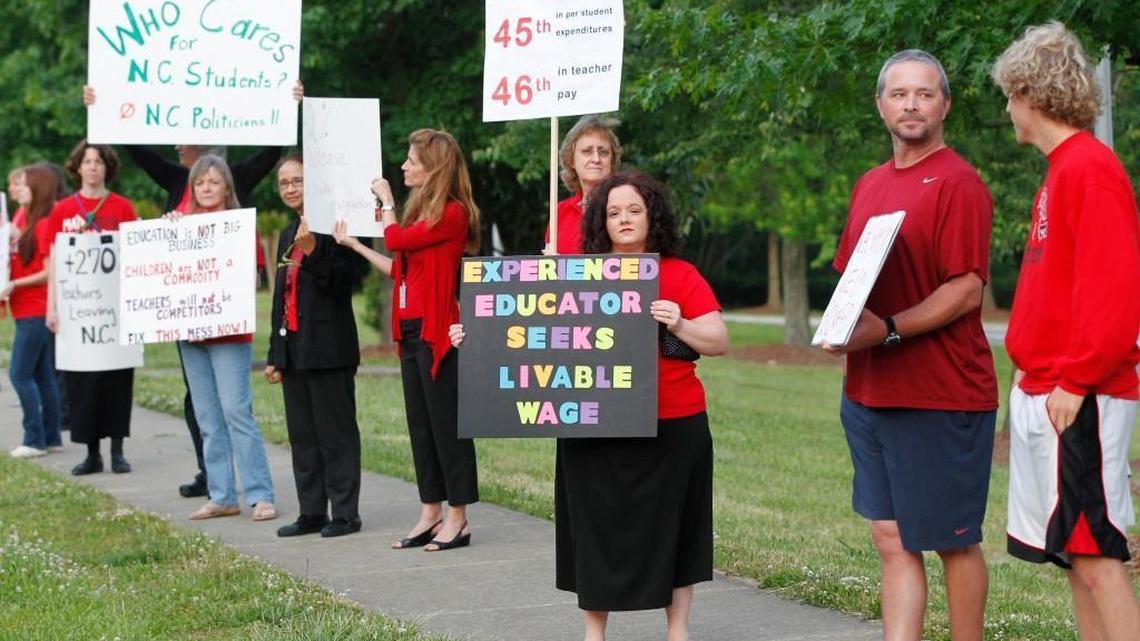 Teachers, including Kristin VanBuskirk, center, a math teacher at Apex High School, rally against high turnover and low pay on the sidewalk in front of Apex High School on May 21, 2014.