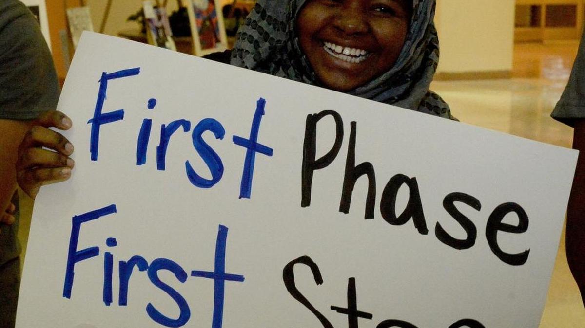 Garinger High School student Asnina Maingua holds up a sign before Wednesday’s Charlotte-Mecklenburg school board meeting, which included a vote on the first phase of student assignment changes.
