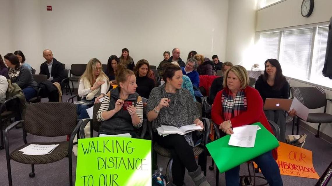 Parents supporting neighborhood schools brought signs to Thursday’s CMS policy committee meeting.
