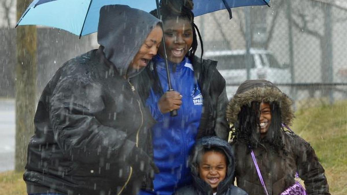 (L to R) Aisha Foster shares an umbrella with her children, Rynaja Wilson, 13, Cameron Hughes, 5, and Ashiyah Hughes, 8, as they walked along Griffith Street during a brief period of heavy rain Monday afternoon.