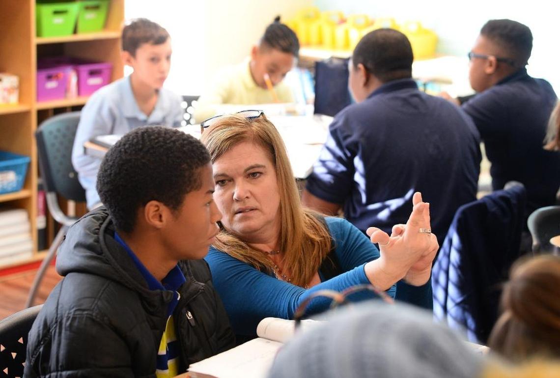 Middle school teacher Kris Poole helps student Miguel Richards with a math problem at Mountain Island Day School, a preK-12 Christian school that will go public in August. School leaders say most of their teachers are already licensed and have experience in public schools.