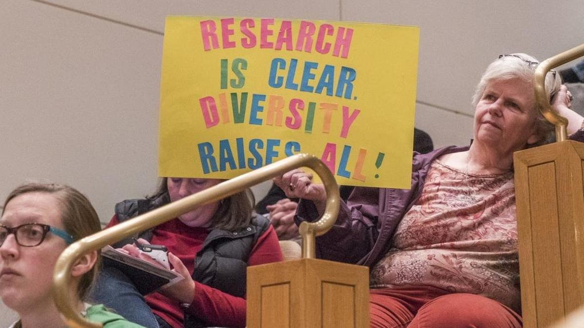 A February hearing on student assignment drew an overflow crowd, many bearing signs.