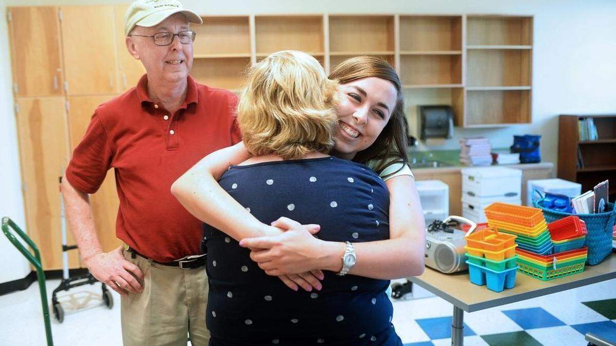 
New teacher Carly Deal hugs her mother, retired teacher Pam Deal, while her father Brent Deal, a photographer, looks on. Her parents just helped Carly Deal move into a new classroom at Lawrence Orr Elementary School.
