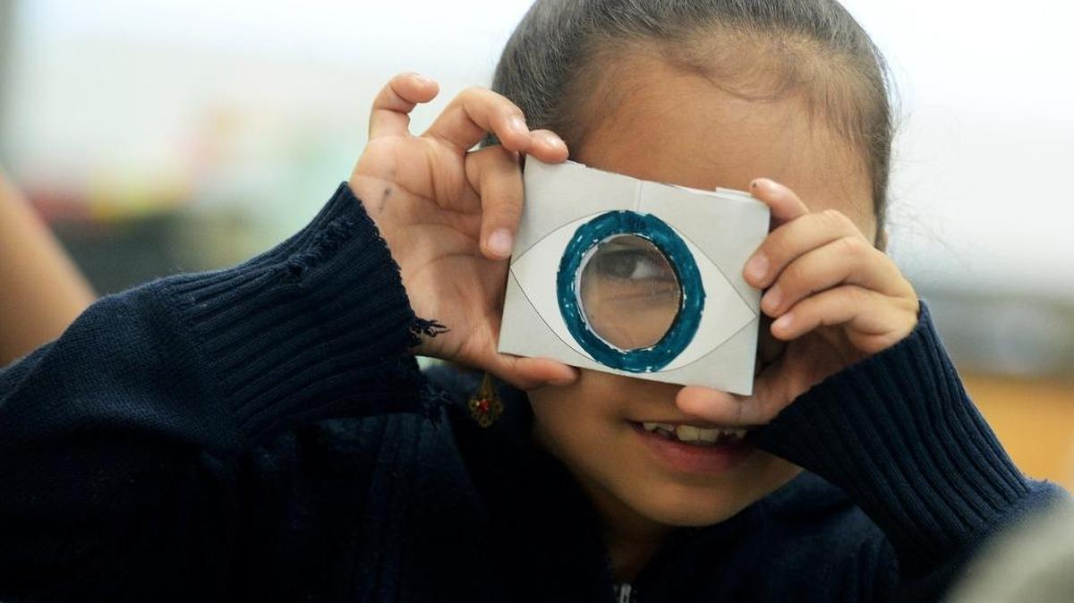 Jessica Espinoza, 7, looks through a device that replicates a cornea of the eye, to see how the eye flips an image at a certain distance, during Saturday’s final STEM session of the year at Ashley Park Elementary.