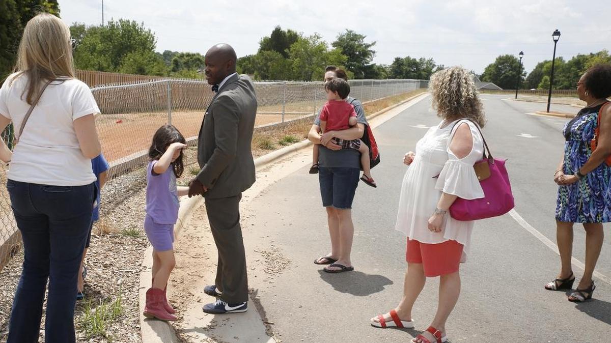 Thunderbird Prep Principal Emmanuel Vincent leads a group on a tour of the Cornelius charter school that’s under intense state scrutiny.