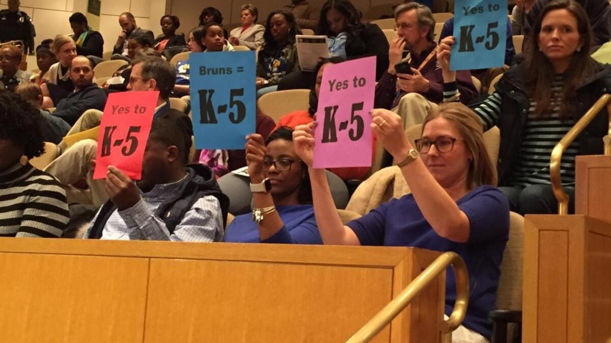 People at Tuesday’s school board meeting show support for returning Bruns Academy to an elementary school.