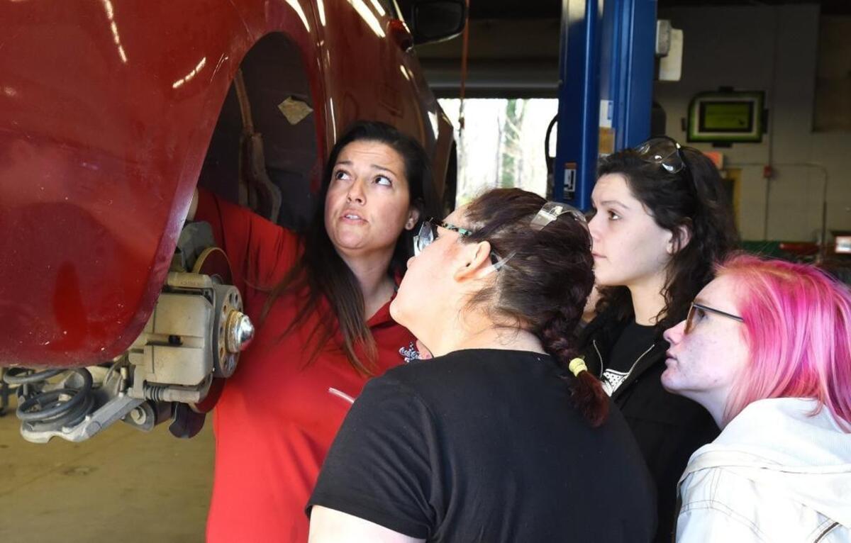 Kristina Carlevatti (left), Myers Park auto mechanics instructor, works with students Evelyn Harris, Isabella Evans and Hannah Cranford (left-right) in class Monday.