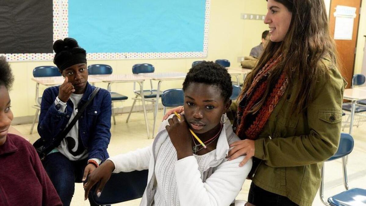 Ashley Park science teacher Samantha Caen (standing) rests her hands on Dianne Klay’s shoulders during the STEAM Saturday class she leads for high-scoring students.