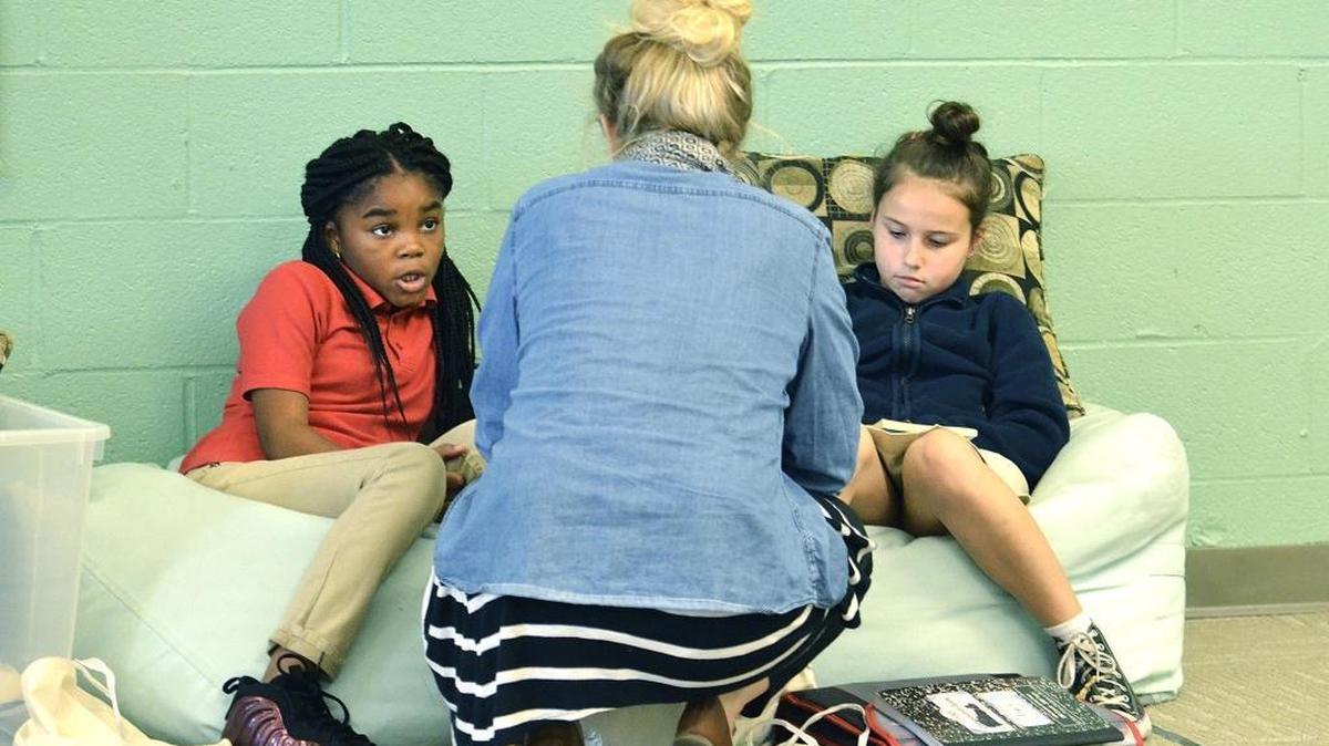 Charlotte Lab School teacher Maggie Brown talks with third-graders Sanai Wilson (left) and Lindsey Osman in March.