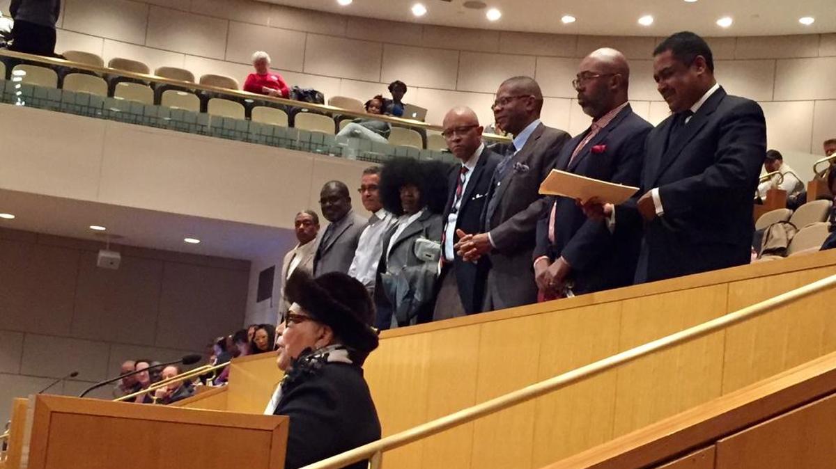 African American clergy supporting the call for a renewed focus on equity stand while Mecklenburg County Commissioner Vilma Leake speaks to the Charlotte-Mecklenburg school board.