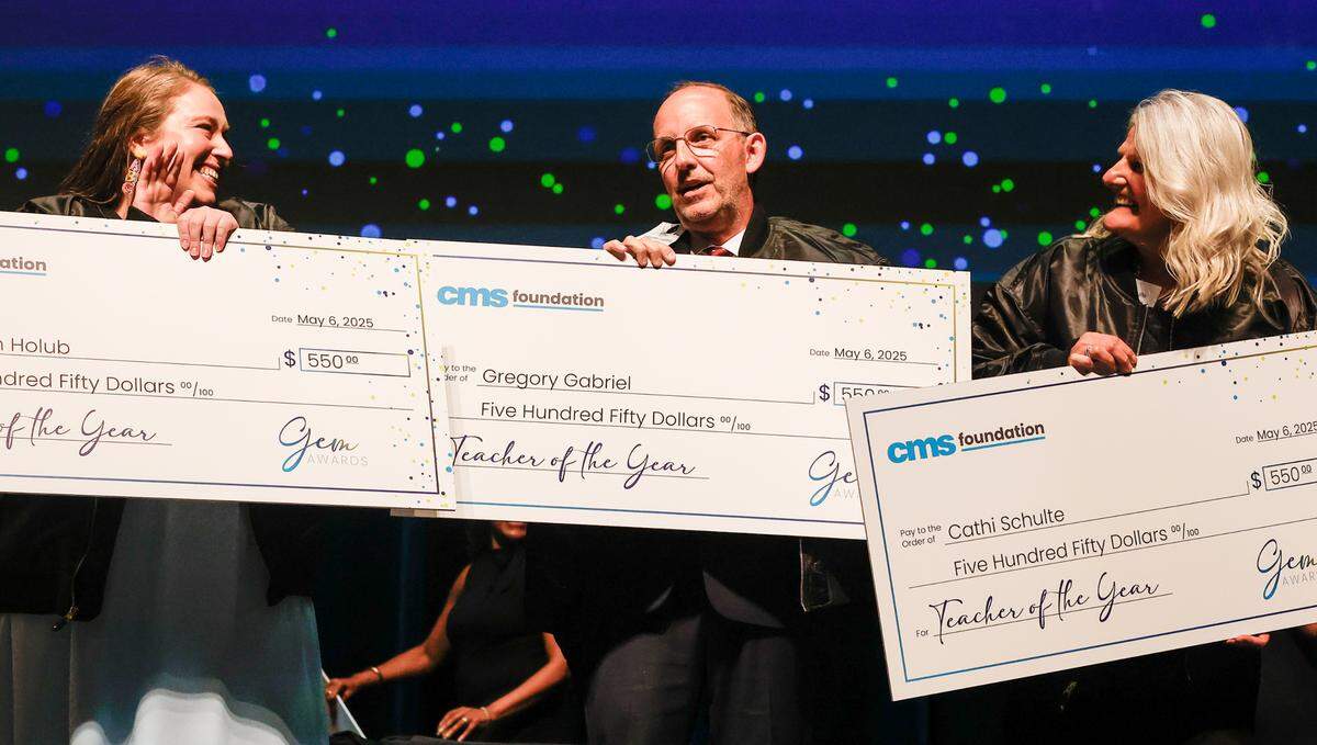 Gregory Gabriel, center, is surrounded with applause as he is named Teacher of the Year by Charlotte-Mecklenburg Schools during the third annual Gem Awards ceremony at Dale F. Halton Theater at Central Piedmont Community College in Charlotte, NC on Tuesday, May 6, 2025. Gabriel, who is a teacher at Winterfield Elementary School, was honored along with the school district’s 2024-25 Teacher Assistant and Beginning Teacher of the Year.