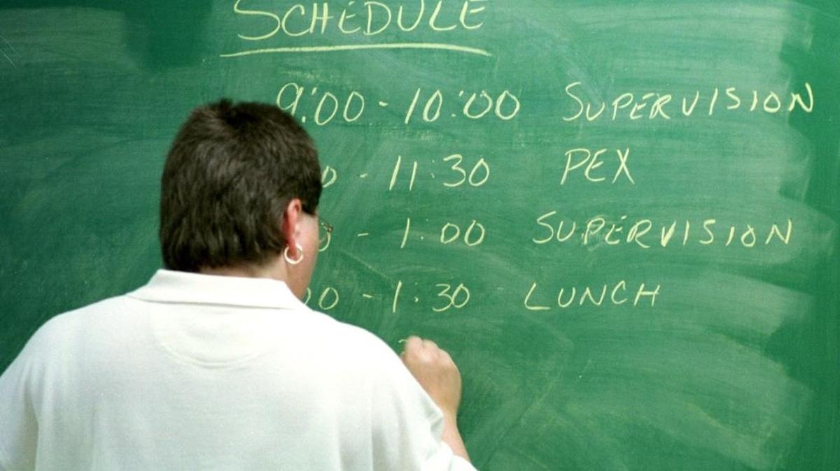 A teacher writes the schedule for the day on a blackboard.