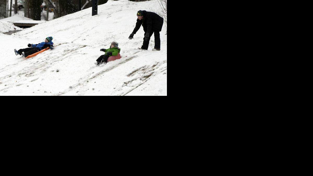 
Adam Harvey (right) gives his son Kellan, 2, a slight push along a slope, as son Aiden (left), 7, leans back and slides at Freedom Park on Tuesdayafter an early morning dusting of snow.
