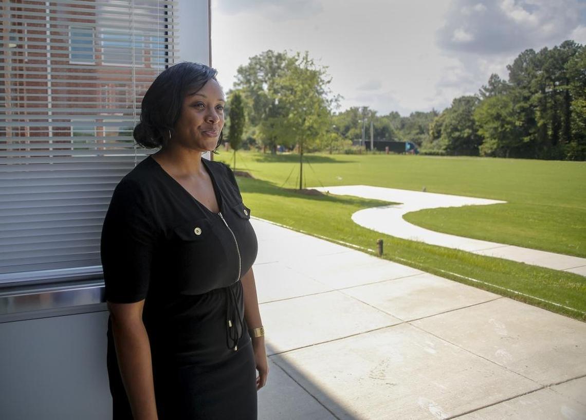 Principal Erin Barksdale demonstrates how a roll-up door in the middle school art class lets students out into a sunny yard that will eventually include a soccer field.
