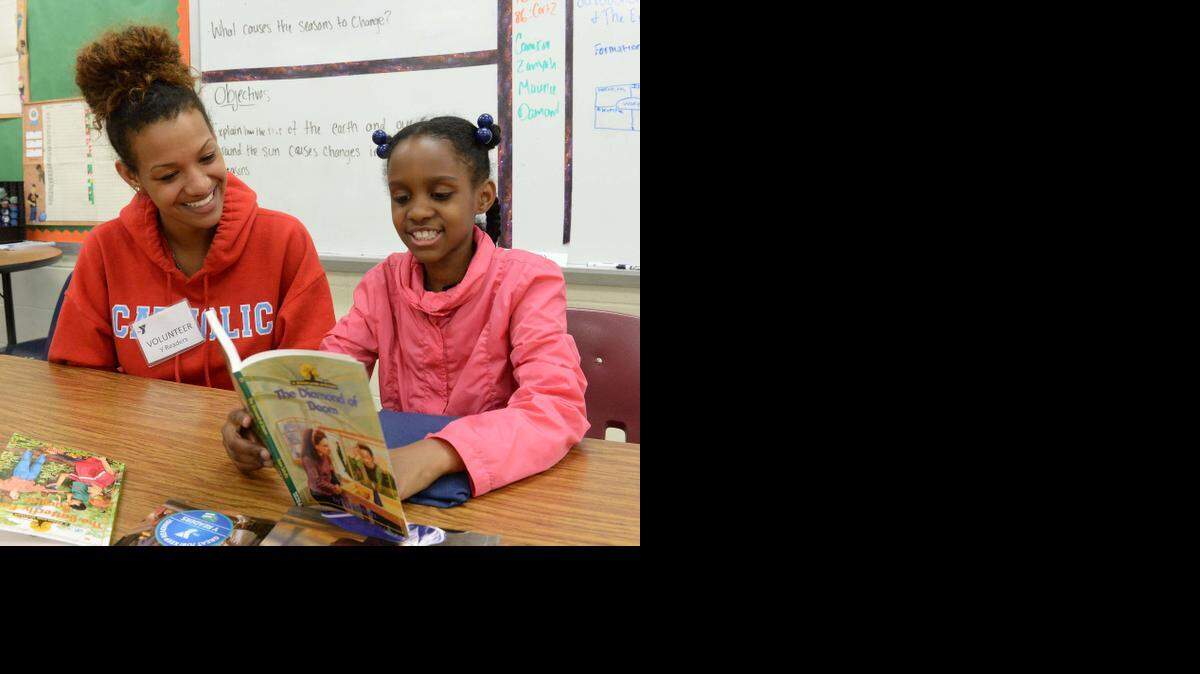 
 YMCA millennial volunteer Arianne Barnwell 17, left, a senior at Charlotte Catholic, helps third-grader Breanna Howey 8, right, with her reading at Reid Park Elementary on April 13, 2015.
