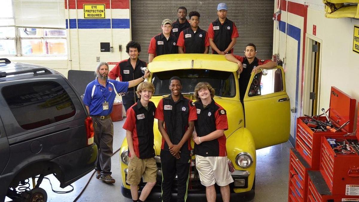 North Mecklenburg High School juniors and seniors in the Advanced Automotive Studies class gather around the 1954 chevy 3100 pickup truck they helped restore on Thursday, May 12, 2016. (L-R front row) Michael Castelli, 17, Gregory Shanks, 16, Cody McKenzie, 17; (row two) Jarod Brown, instructor, Jesus Rios, 17, Jan Bracero (far right), 18; (back row of four) Seth Siniard, 18 Raymond Banks, 18, Jalen McDonald, 18 and Brandon Burge, 17. Jarod Brown, a CMS CTE Automotive instructor at North Mecklenburg High School and his automotive studies students have restored a yellow 1954 Chevy 3100 pickup truck.