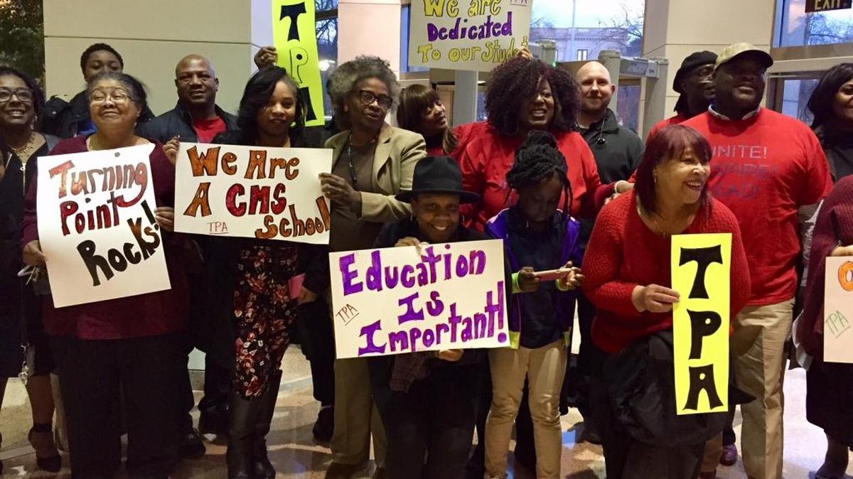Teachers, families and other advocates for Turning Point Academy pose for photos after making dramatic public comments at Tuesday’s school board meeting.