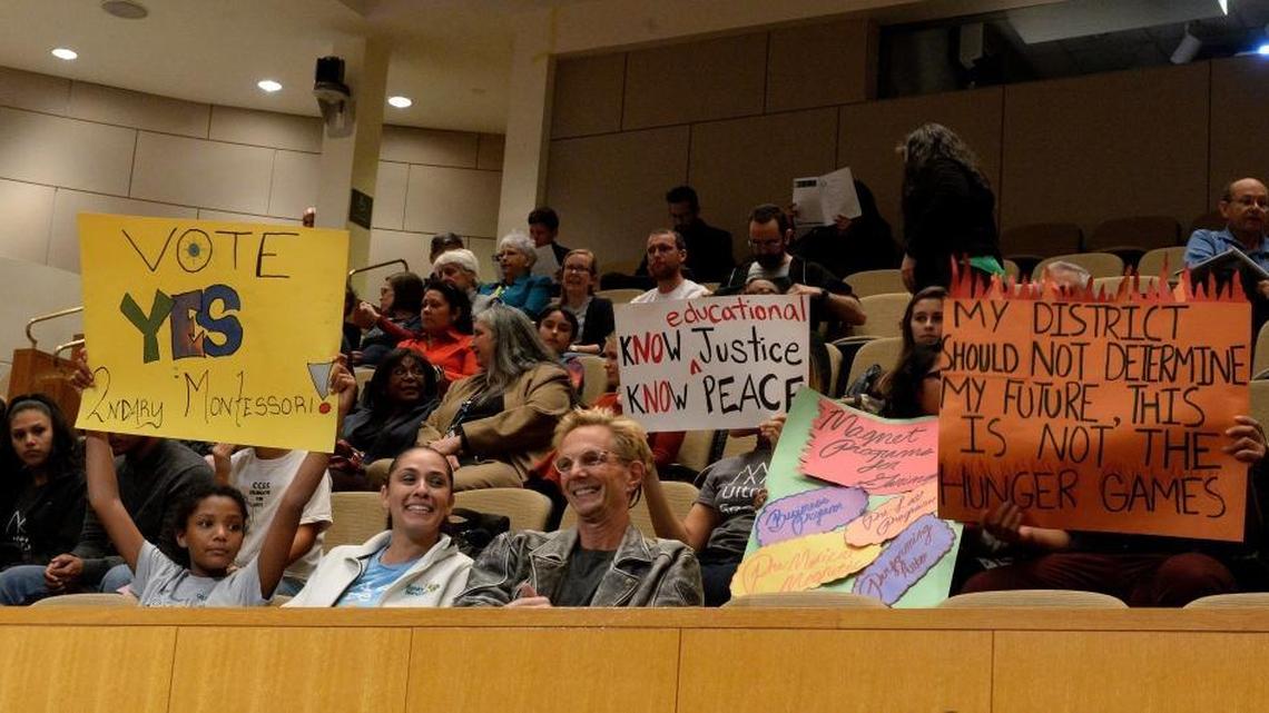 Students hold signs related to student assignment at Wednesday’s Charlotte-Mecklenburg school board meeting.