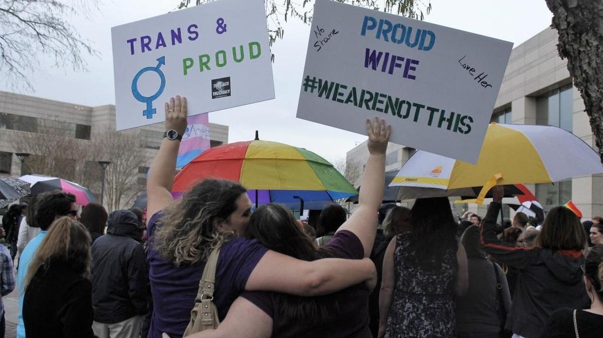 Two protesters hold up signs against passage of legislation in North Carolina, which limits the bathroom options for transgender people, during a rally in Charlotte onThursday.