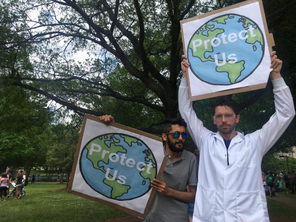 Behrooz Bajestani, left, and Austin Willoughby hold signs calling for environmental policies to protect against climate change.