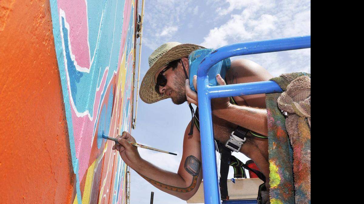 
 Charlotte artist Will Puckett works on giant mural across the top of the Neighborhood Theatre on July 08,2015.

