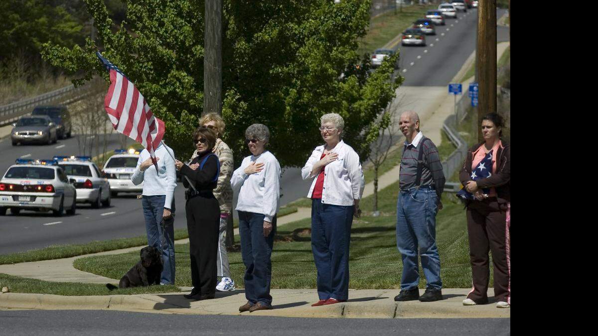 
Residents of the Providence Commons neighborhood along Providence Road pay tribute as the hearse carrying the body of CMPD Officer Sean Clark heads toward the cemetery in 2007. 
