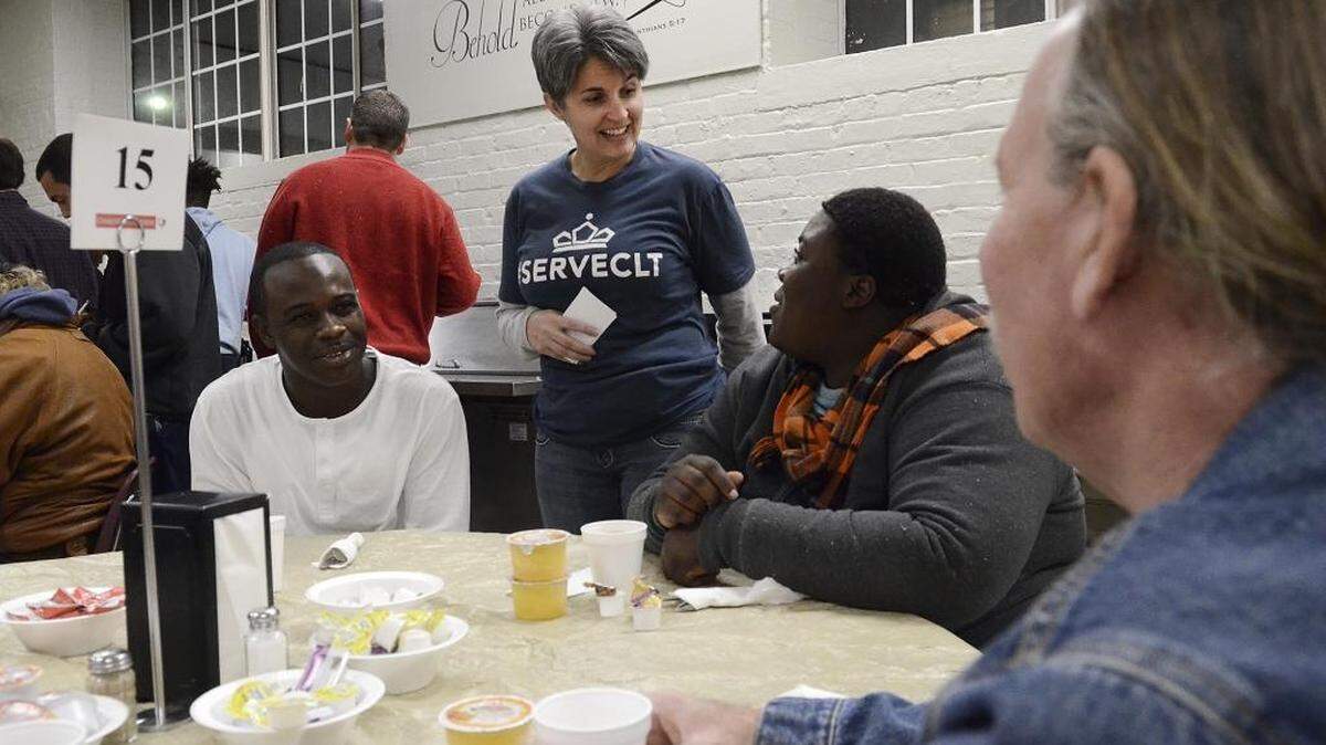 Volunteer server Tricia Oles chats with diners (L-R) Michael Brown, Gamba Takassi and Randy Johnson before their breakfast arrived at the Charlotte Rescue Mission. Hundreds of Charlotte's homeless were able to get a Thanksgiving meal at the Charlotte Rescue Mission on Thursday, Nov. 26, 2015. The kitchen was ably with volunteers from about 5am. Breakfast was served, restaurant style, with smiling servers taking orders from diners who later delivered plates of food to their tables.