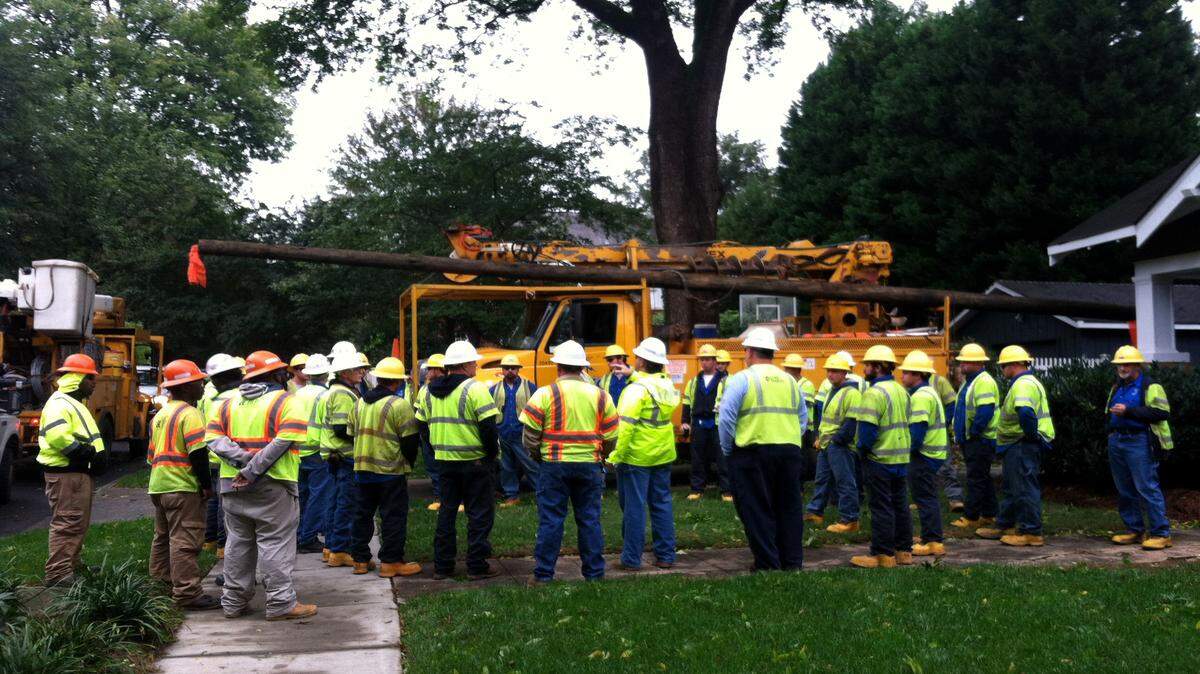 Utility workers plan their strategy early Sunday on how to restore power to part of Charlotte's Dilworth neighborhood, where a huge oak crashed around 4 p.m. Saturday, taking the power line with it.