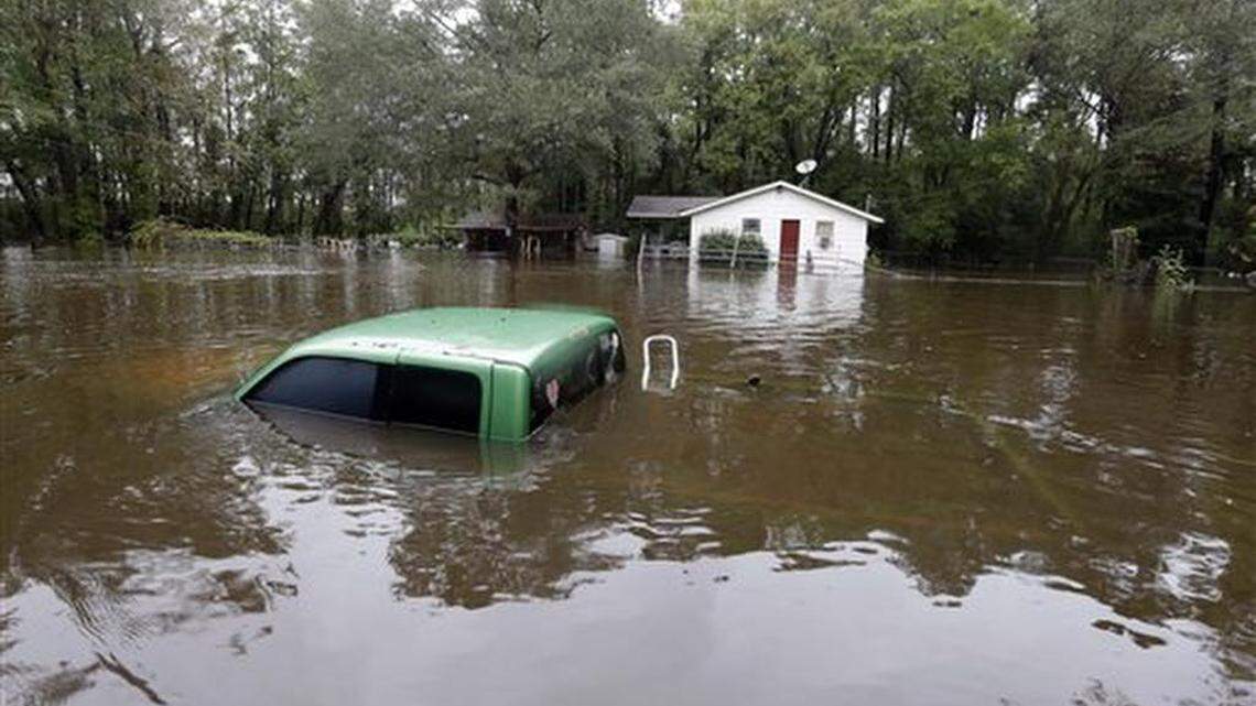 A vehicle and a home are swamped with floodwater from nearby Black Creek in Florence, S.C., Monday, Oct. 5, 2015 as flooding continues throughout the state following several days of rain.