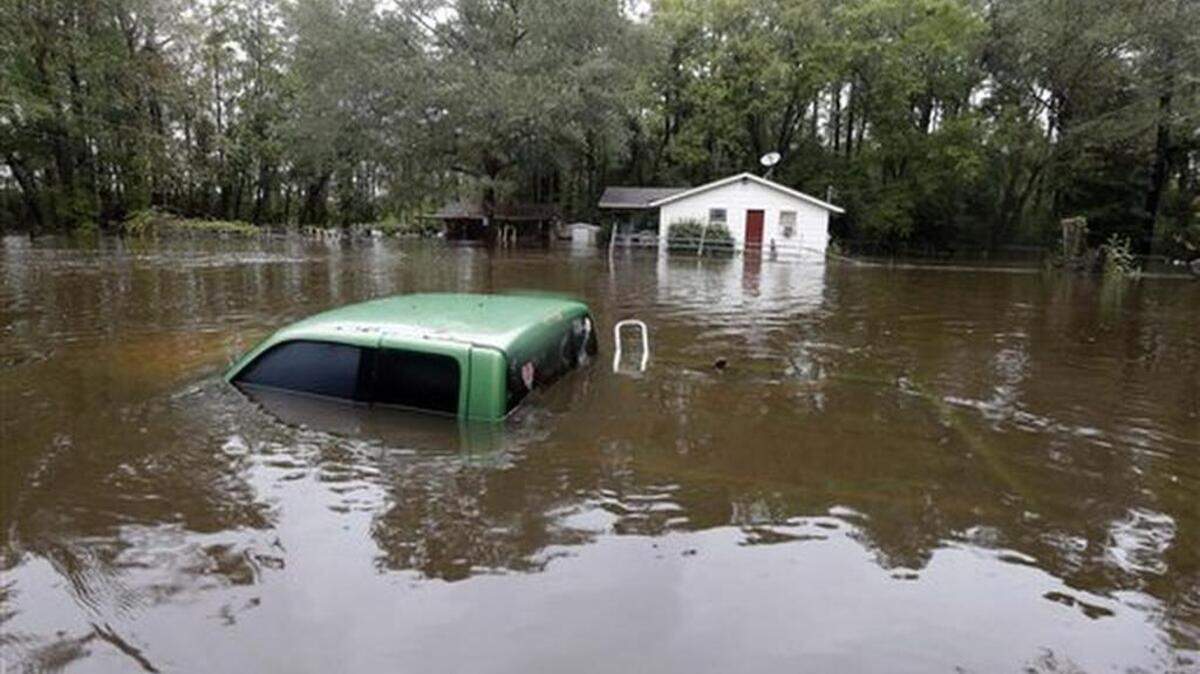 A vehicle and a home are swamped with floodwater from nearby Black Creek in Florence, S.C., Monday, Oct. 5, 2015 as flooding continues throughout the state following several days of rain.