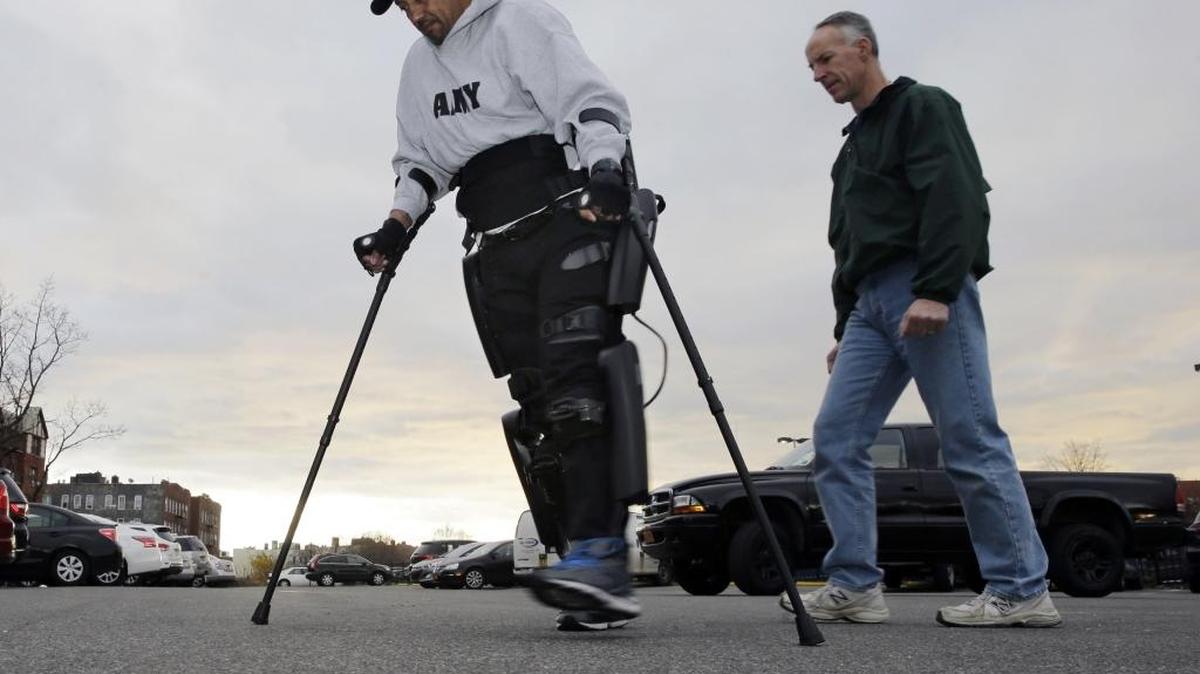 ReWalk Robotics service engineer Tom Coulter, right, looks on as paralyzed Army veteran Gene Laureano makes a turn while he walks using a ReWalk device Wednesday, Dec. 16, 2015, in Bronx, N.Y. The Department of Veterans Affairs has agreed to pay for robotic legs that could allow scores of paralyzed veterans with spinal cord injuries to walk again.
