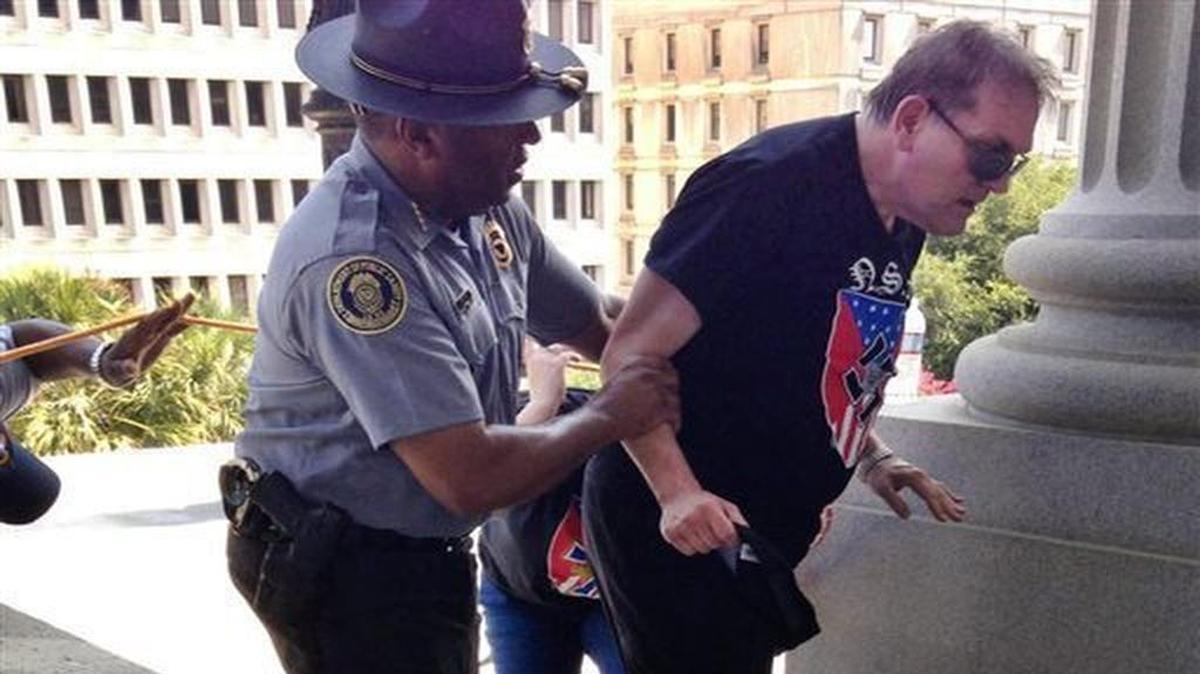 
S.C. Department of Public Safety Director Leroy Smith helps someone wearing National Socialist Movement attire get to shade and water during a Ku Klux Klan rally Saturday at the State House. 
