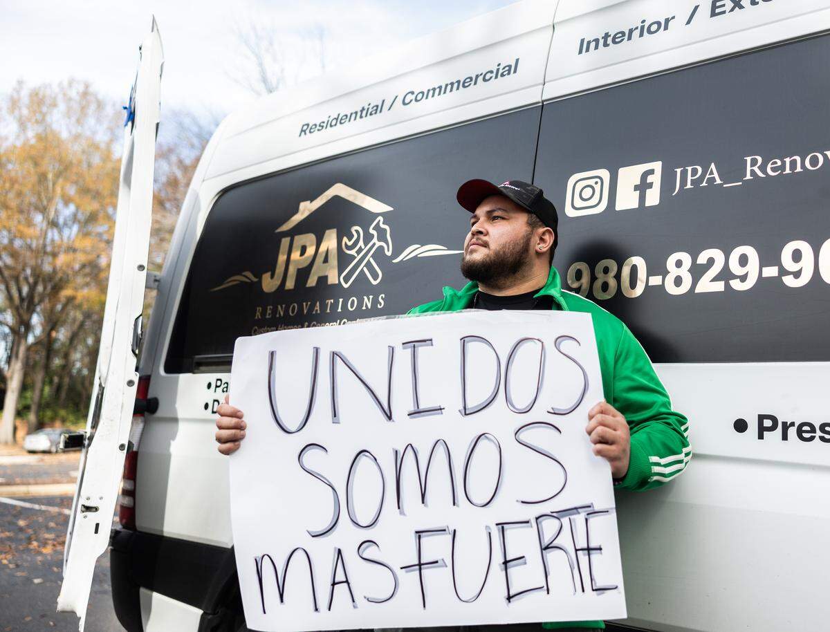 Jesse Pacheco holds up a protest sign by his work truck in Charlotte on Monday, November 24.